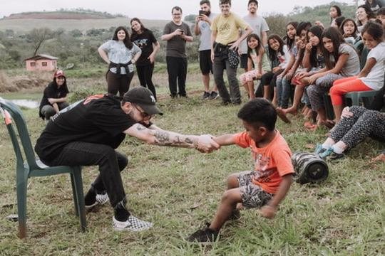 Matheus brincando de cabo de guerra com um menino, com outras crianças em volta