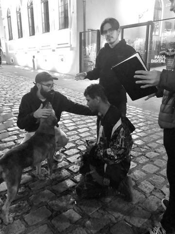 Matheus orando com um homem em situação de rua, ao lado de um cachorro